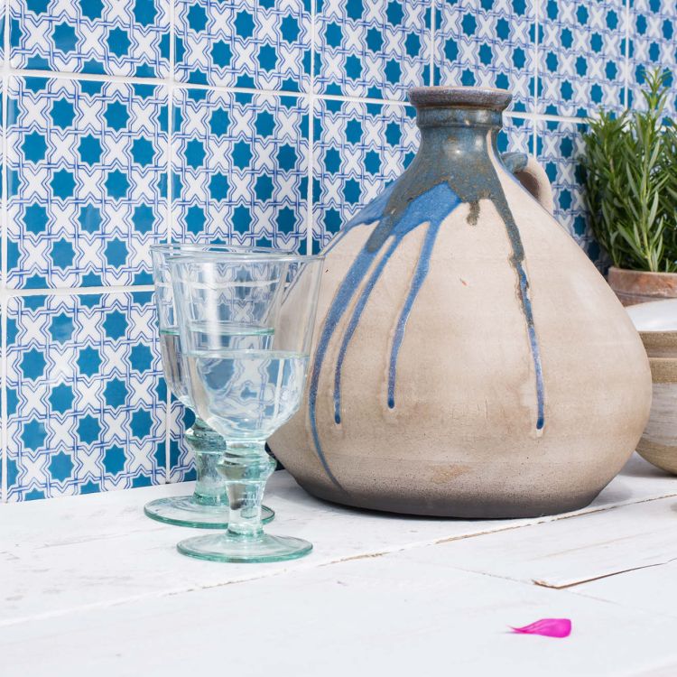 Rustikaler Krug und Wassergläser vor blauen Fliesen