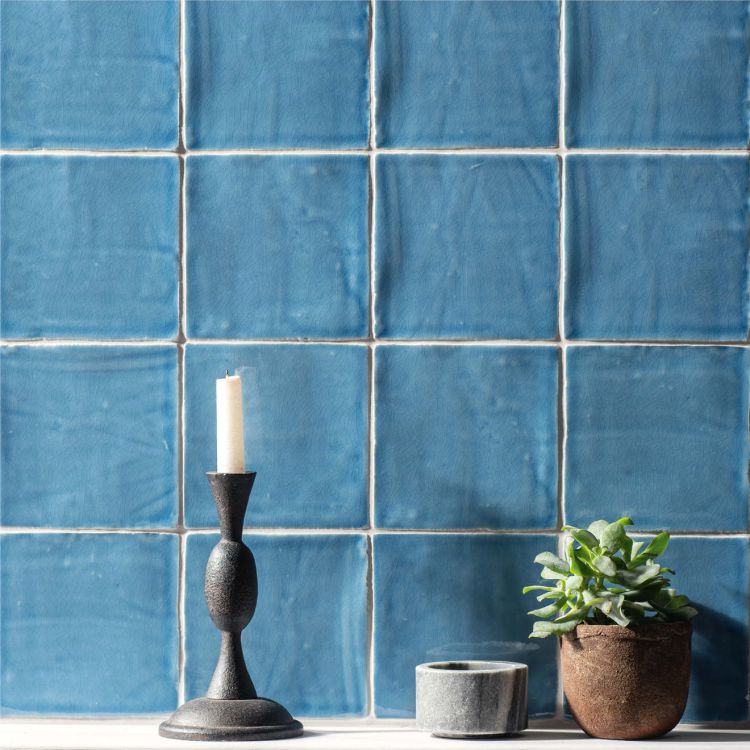 Blaue Wandfliesen, matte Glasur mit Kerze und Pflanze