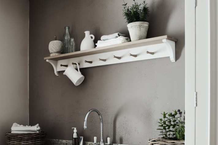 Moderne Küchenwand mit dekorativem Wandregal aus Holz und mehreren Haken, ideal für stilvolle Aufbewahrung Helles Wandregal mit Haken in einer Küche, dekoriert mit Geschirr, Vasen, Handtüchern und Pflanzen über einem Waschbecken