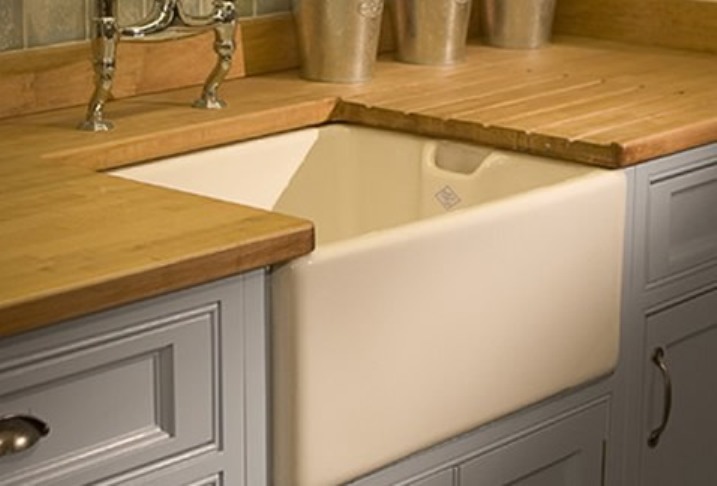 Landhausstil Keramikspüle mit Arbeitsplatte aus Holz in moderner Küche Weiße Keramikspüle im Landhausstil, eingebaut in eine Holzar-beitsplatte mit grauen Küchenfronten und silbernen Griffen