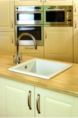 Moderne Einbauküche mit Edelstahlgeräten und weißem Spülbecken Küche mit hellen Fronten, integriertem Backofen, Mikrowelle und großem weißen Spülbecken auf einer Holzarbeitsplatte