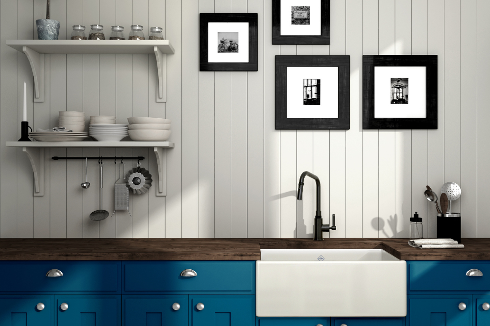 Produktfoto: weiße Keramik-Küchenspüle im Landhausstil mit schwarzer Armatur, Holzarbeitsplatte und blauen Unterschränken; offene Regale mit Geschirr im Hintergrund