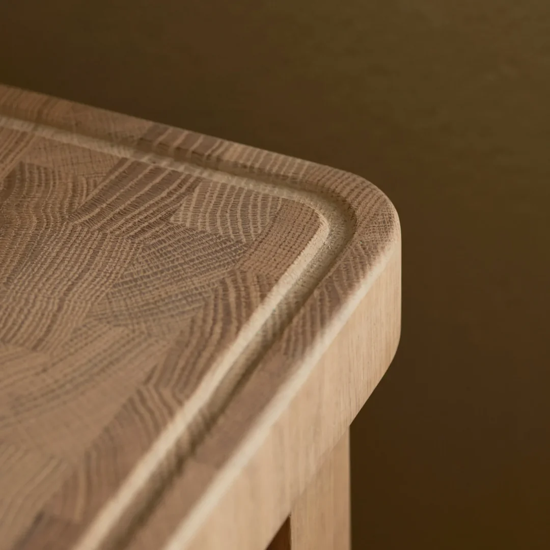 Detailaufnahme einer Eiche-Massivholz-Tischplatte mit abgerundeter Ecke und umlaufender Fräsnut; feine Holzmaserung für edle Tische