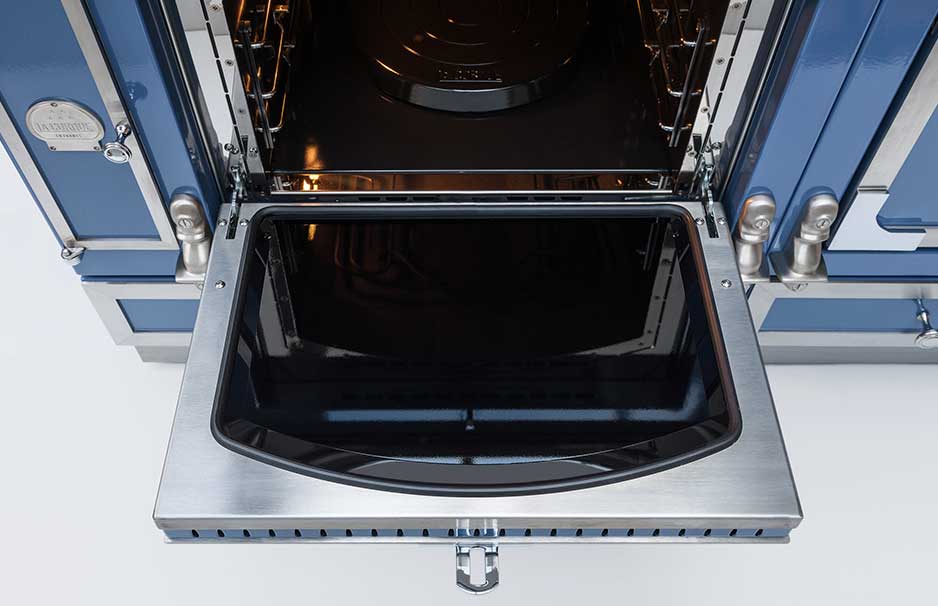 Geöffneter moderner Backofen mit blauer Front und Edelstahl-Backblech Detailansicht eines geöffneten Backofens mit aufgeklappter Tür und herausnehmbarem Backblech, blaues Design mit Edelstahl-Elementen