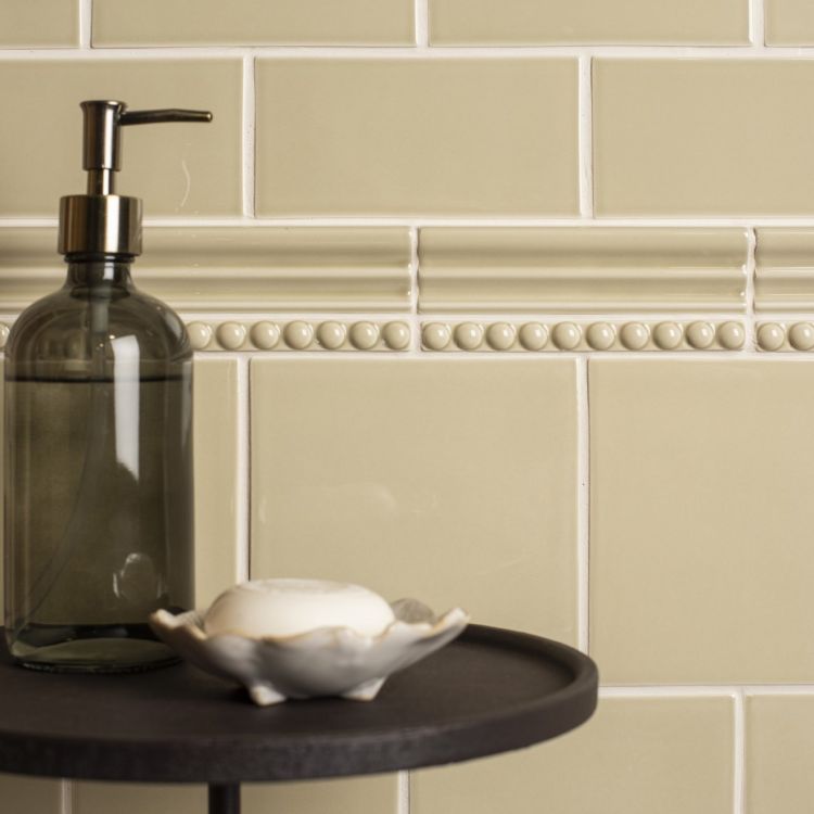 Beige Badfliesen mit Bordüre, Seifenspender daneben