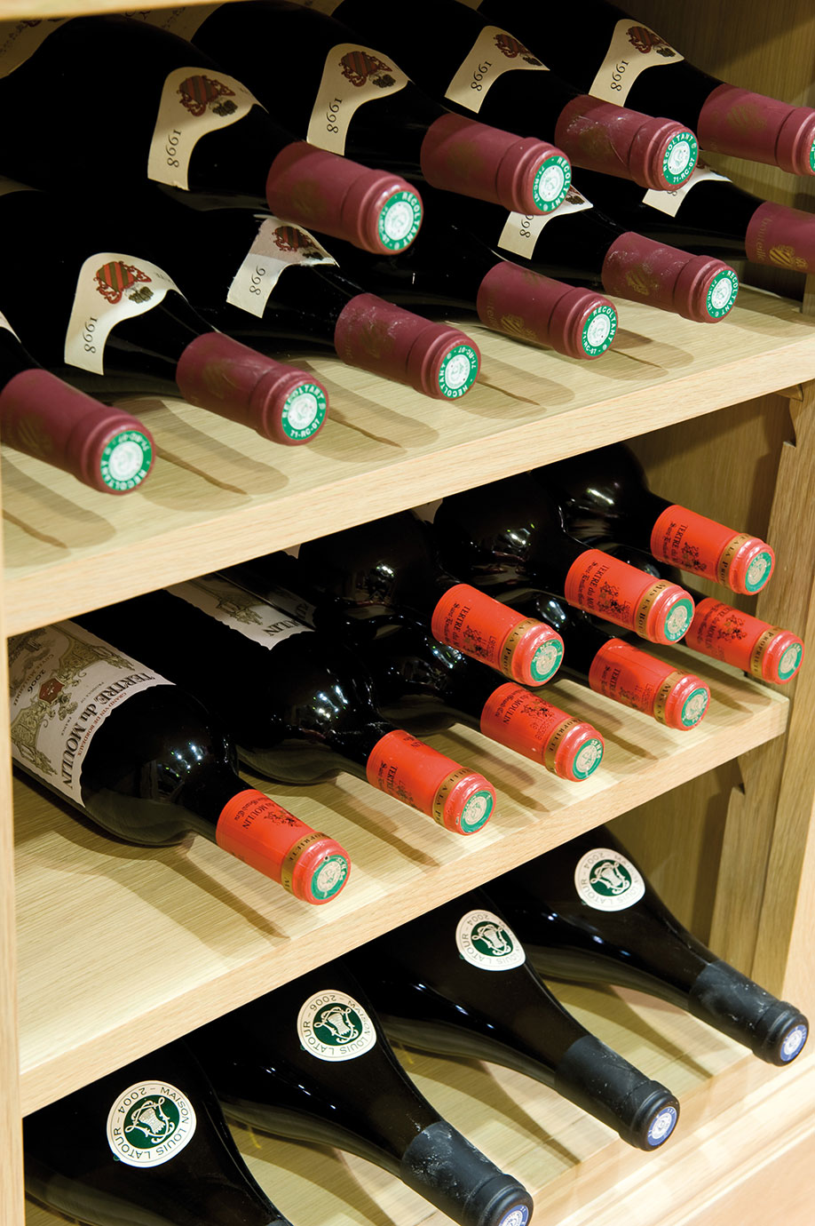 Edles Weinregal mit verschiedenen Weinflaschen für Genießer Weinregal aus Holz mit mehreren gelagerten Weinflaschen unterschiedlicher Jahrgänge und Etiketten