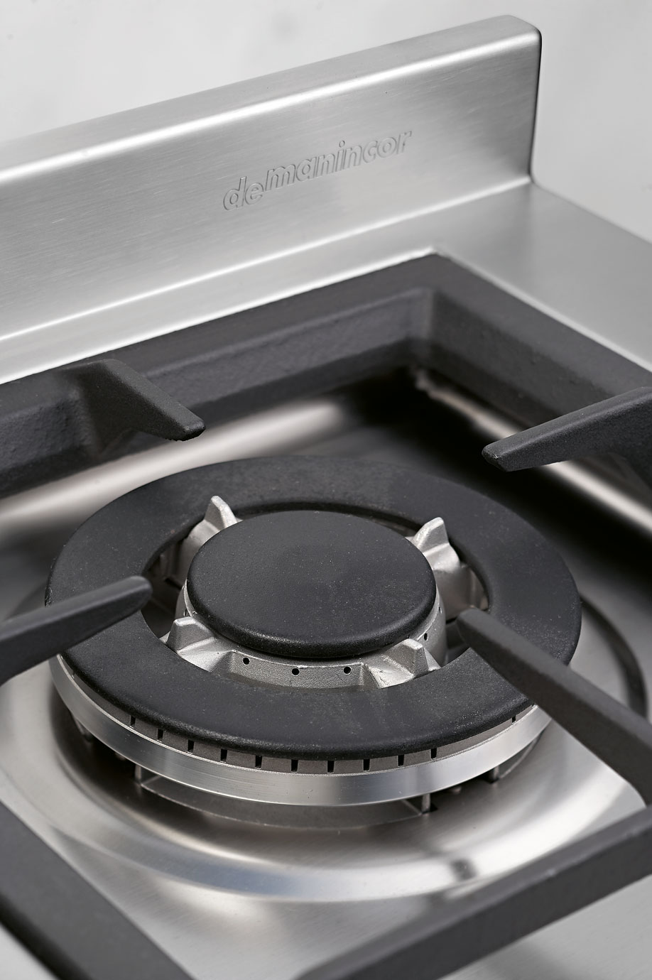 Hochwertiger Edelstahl-Gasherd von deManincor mit robustem Kochfeld Detailaufnahme eines Gasherds von deManincor aus Edelstahl mit stabilem Brenner und Gusseisenrost