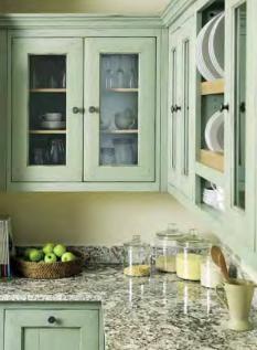 Landhausstil-Küche mit mintgrünen Schränken und Granit-Arbeitsplatte Küchenzeile mit mintgrünen Oberschränken mit Glastüren, Granit-Arbeitsplatte, Obstkorb mit grünen Äpfeln und Vorratsgläsern