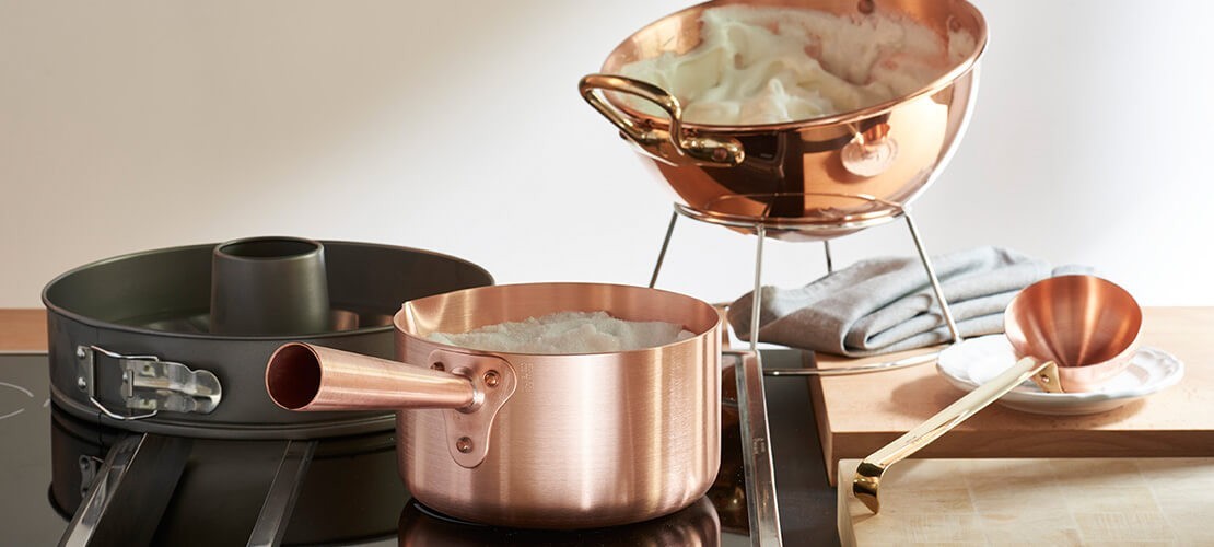 Verschiedene Kupfertöpfe und Backutensilien auf einem Herd, ideal für stilvolles Kochen und Backen.
