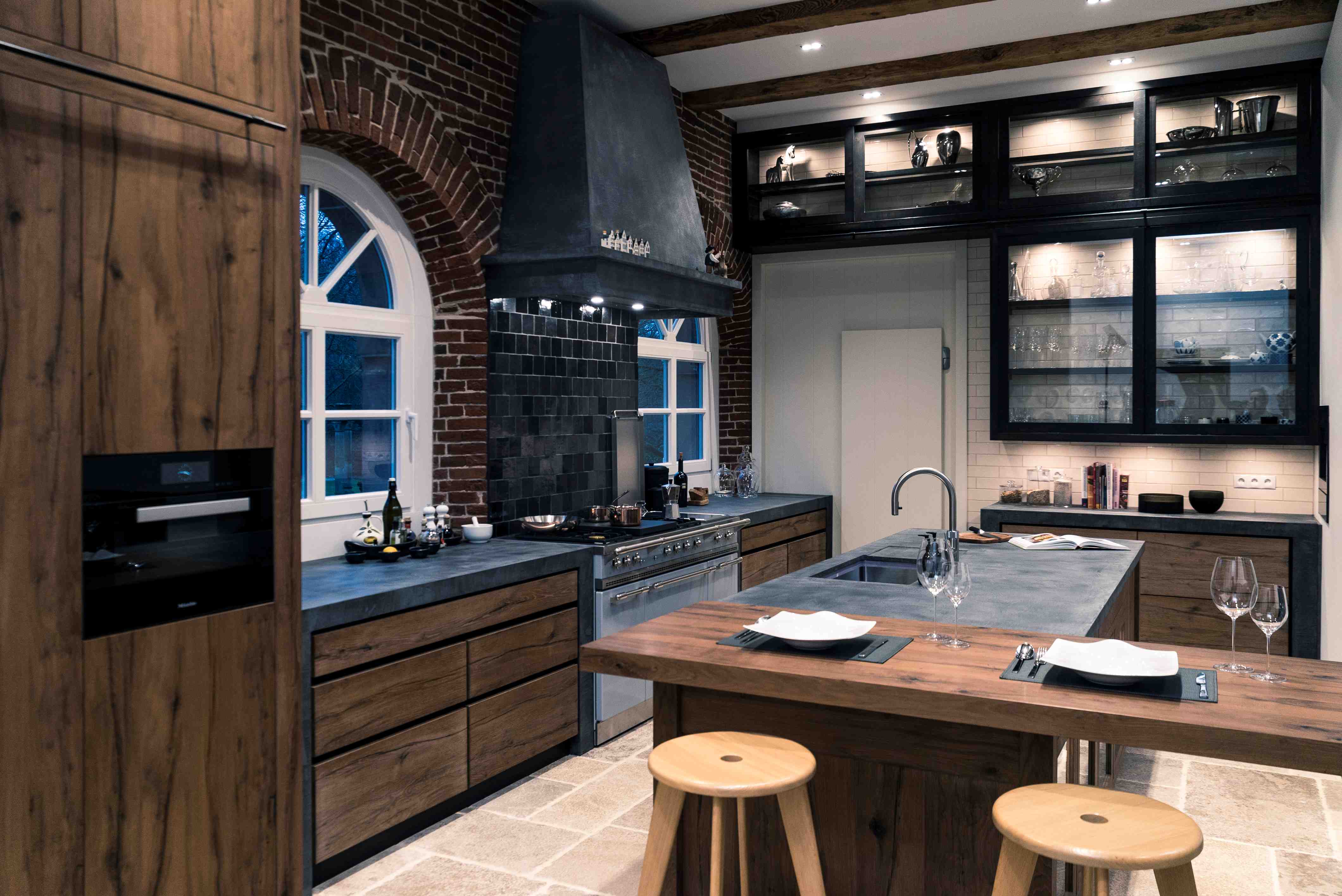 Moderne Wohnküche mit Holzfronten, Kücheninsel und hochwertiger Ausstattung Geräumige, moderne Küche mit Fronten in Holzoptik, Kücheninsel mit Sitzplätzen, großem Herd, Backofen, schwarzen Fliesen und dekorativer Beleuchtung