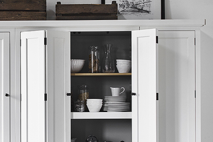 Weißer Küchenschrank mit geöffneten Türen und stilvoll arrangiertem Geschirr Offener weißer Schrank mit Tellern, Tassen, Gläsern und Schalen in modernem Design