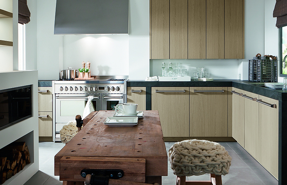 Moderne Küche mit Holzfronten, großer Arbeitsfläche und Esstisch aus Massivholz Helle, moderne Küche mit Holzschränken, großem Gasherd, Esstisch aus Massivholz und Hockern mit gestrickten Sitzkissen