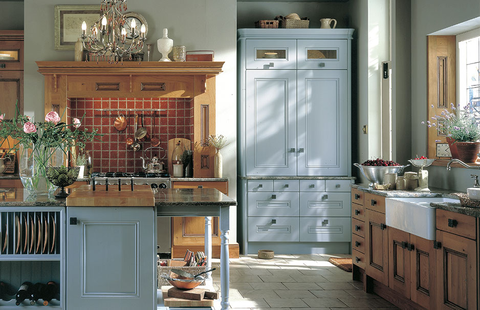 Landhausküche mit Holzelementen, heller Kücheninsel und traditionellem Herd Helle Landhausküche mit Kücheninsel, großem Vorratsschrank, Holzelementen, Deckenleuchter, Spüle und liebevoll dekorierten Arbeitsflächen