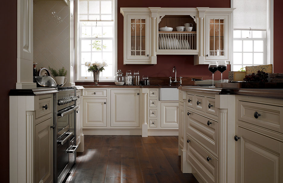 Klassische Landhausküche mit cremefarbenen Massivholz-Fronten und moderner Ausstattung Elegante Landhausküche mit cremefarbenen Schränken, offenem Tellerregal, dunkler Arbeitsplatte und stilvollen Details wie Glastüren und Holzboden