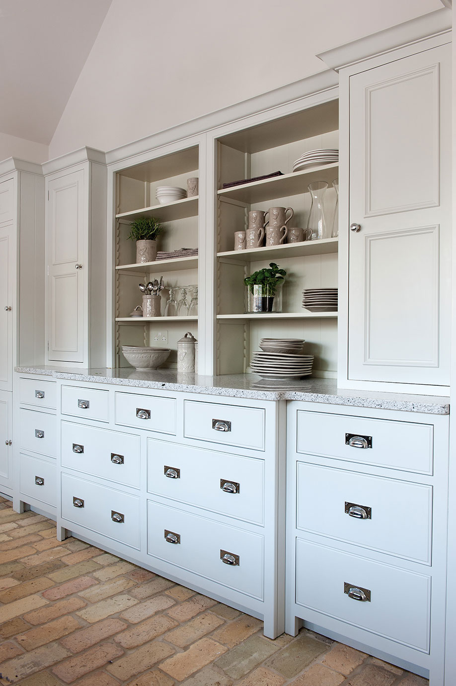 Eleganter weißer Küchenschrank mit offenen Regalen und Schubladen Heller, moderner Küchenschrank mit offenen Regalen, dekorativen Geschirrteilen und vielen Schubladen, auf einem gemauerten Boden stehend