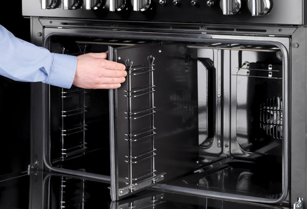 Backofen mit geöffneter Tür und Bedienelementen – modernes Küchengerät Person öffnet einen modernen Backofen mit zwei Klapptüren, sichtbar sind Roste und Bedienelemente.