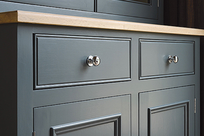 Dunkelgraue Kommode mit Holzplatte und verchromten Griffen – modernes Möbeldesign Detailansicht einer dunkelgrauen Kommode mit Holzplatte und glänzenden Metallknäufen