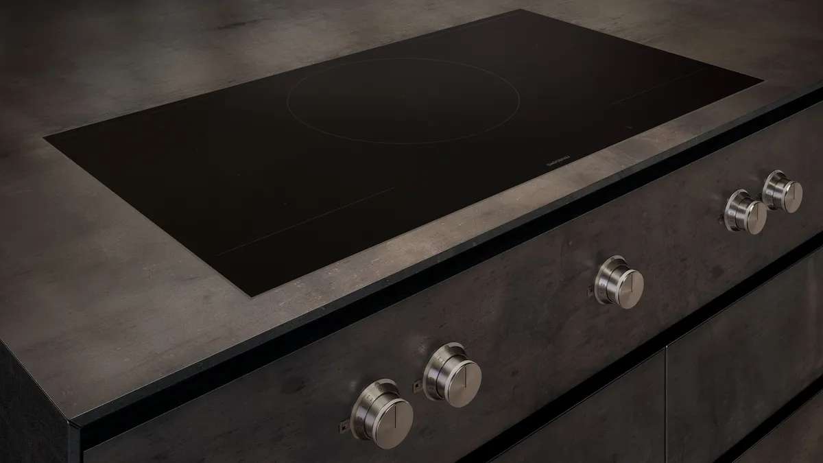 Modernes Induktionskochfeld mit Drehknöpfen in hochwertiger Einbauküche Schwarzes Induktionskochfeld mit eleganten Drehknöpfen, eingebaut in eine moderne Küchenzeile aus dunklem Material