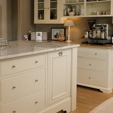 Elegante Küchenzeile mit cremefarbenen Schränken und Marmortheke Moderne Küche mit cremefarbenen Fronten, Marmortheke, Kaffeemaschine und Glaselementen in den Oberschränken