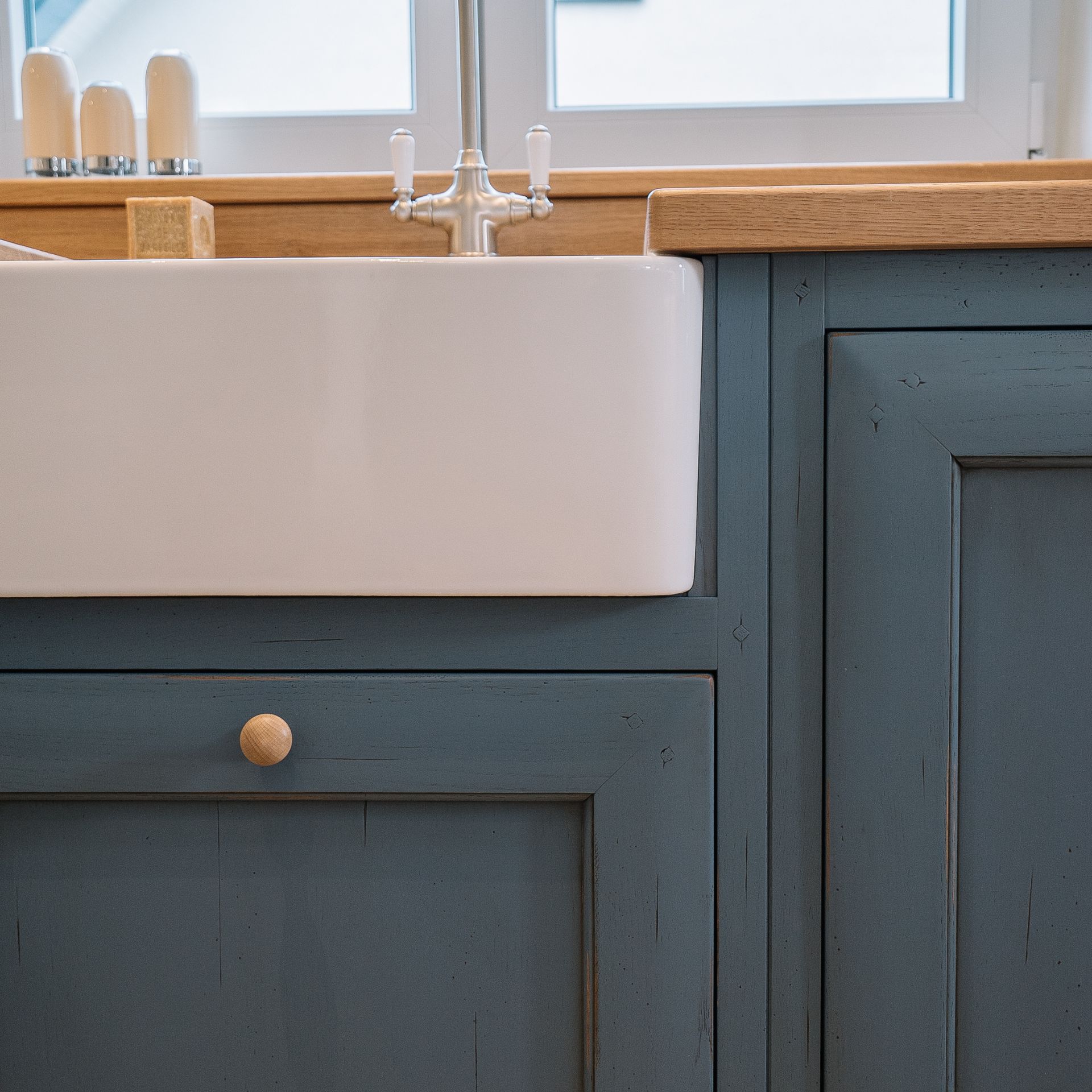 Keramik-Spülbecken im Landhausstil, eingebaut in blauen Shaker-Unterschrank mit Eiche-Arbeitsplatte und Retro-Armatur – hochwertige Küchenspüle