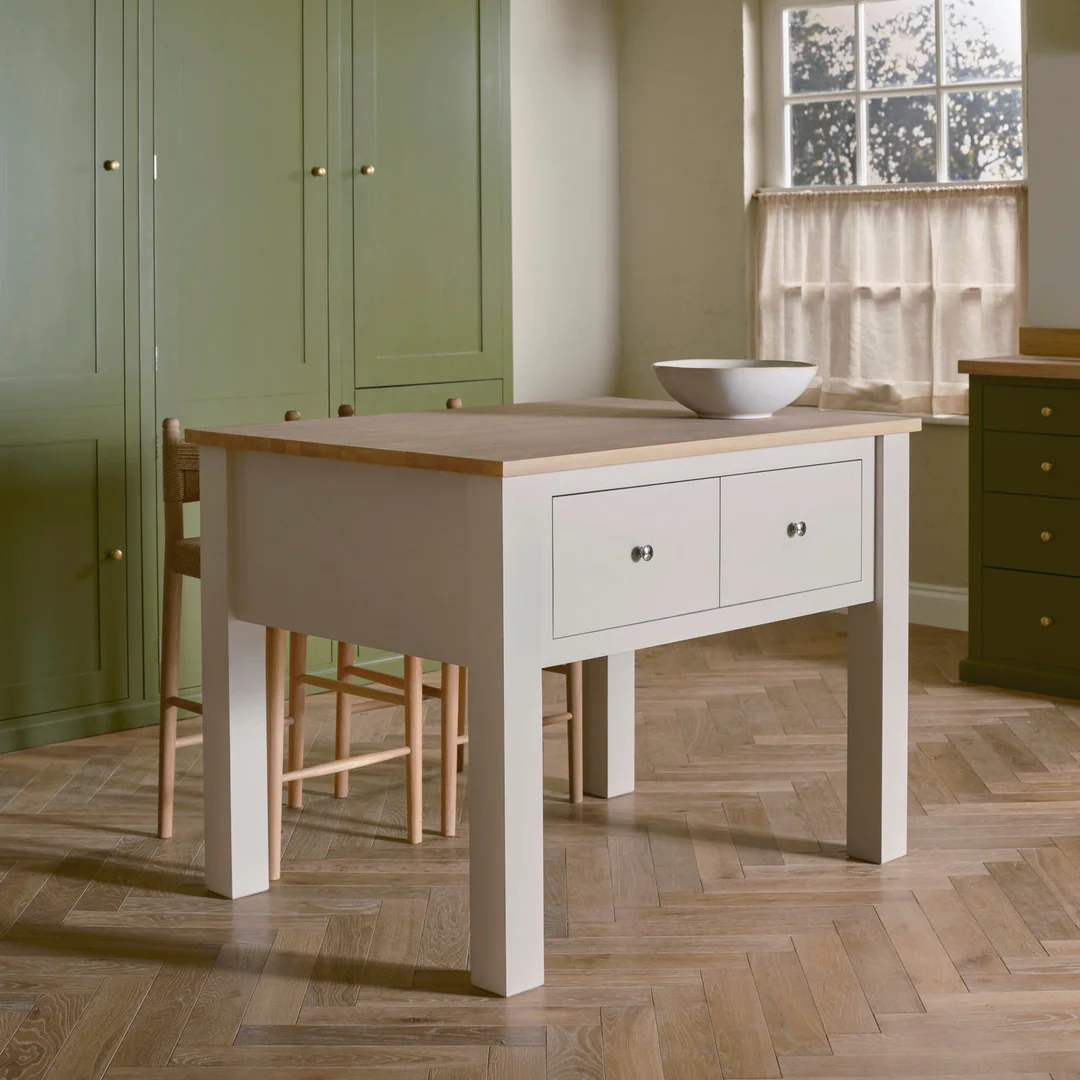 Cremeweiße Shaker-Kücheninsel mit robuster Holzplatte und zwei Schubladen, freistehend, ideal als Arbeits- und Stauraum in der Küche; abgebildet mit Schüssel auf der Platte.