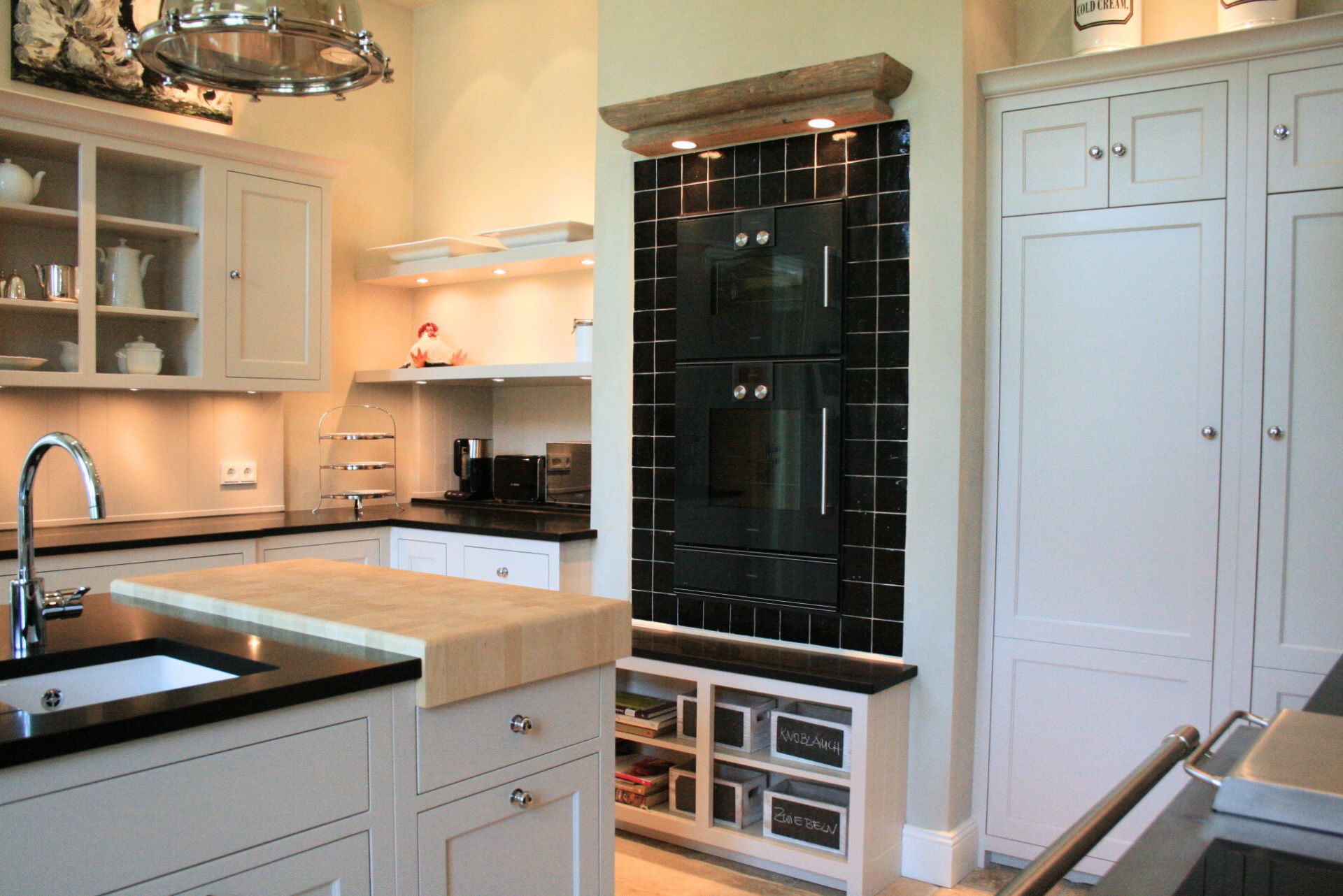 Helle Einbauküche mit Kücheninsel, Holz-Schneidebrett-Aufsatz, schwarzem Doppel-Backofen, offenen Regalen und weißen Schränken