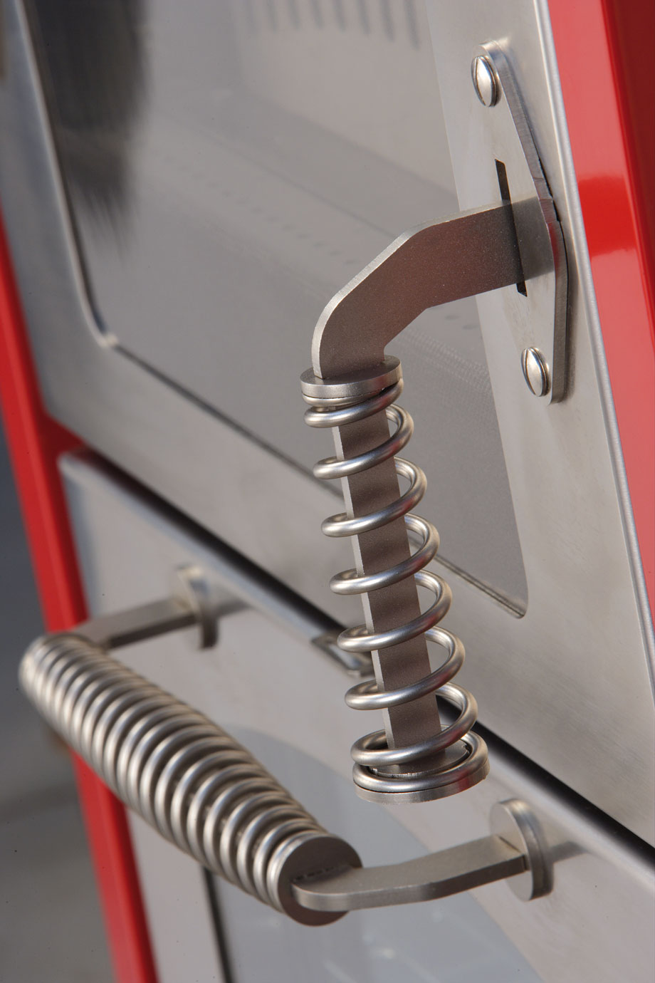 Detailansicht Griff und Verschluss eines Edelstahl-Backofens mit Federmechanik Nahaufnahme von Edelstahlgriffen und -verschlüssen mit Federmechanik an der Tür eines Backofens