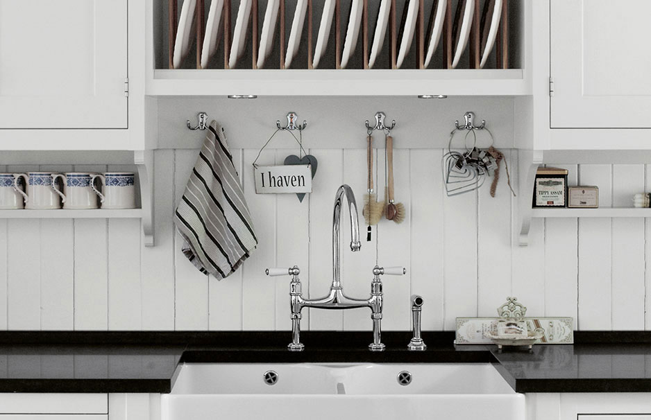 Moderne Landhausküche mit weißem Spülbecken, Wandhaken und offenem Geschirrregal Helle Küche im Landhausstil mit weißem Spülbecken, Hakenleiste mit Küchenutensilien, Tassenregal und geöffnetem Geschirrfach mit Tellern.
