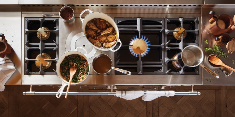 Professioneller Gasherd mit mehreren Töpfen und Pfannen beim Kochen in einer modernen Küche Blick von oben auf einen Edelstahl-Gasherd mit verschiedenen Töpfen, Pfannen und Kochutensilien beim Zubereiten von Speisen
