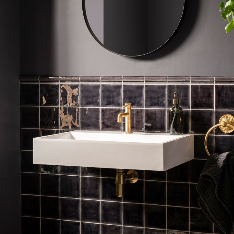 Weißes Wandwaschbecken mit goldener Armatur