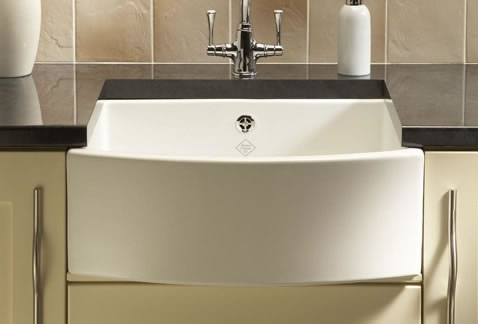 Moderner Küchenwaschtisch aus Keramik mit nostalgischem Design und Armatur Weiße Keramikspüle mit Armatur und Seifenspender auf schwarzer Arbeitsplatte in moderner Küche