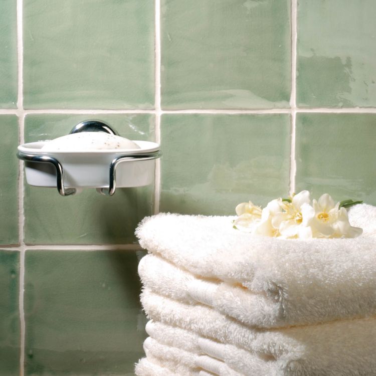 Seifenschale und Handtuchstapel vor grünen Fliesen