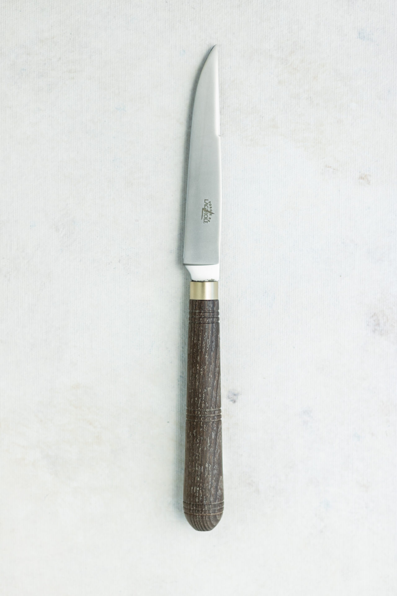 Elegantes Küchenmesser mit Holzgriff – ideal für präzises Schneiden Küchenmesser mit rostfreier Klinge und dunklem Holzgriff auf heller Unterlage