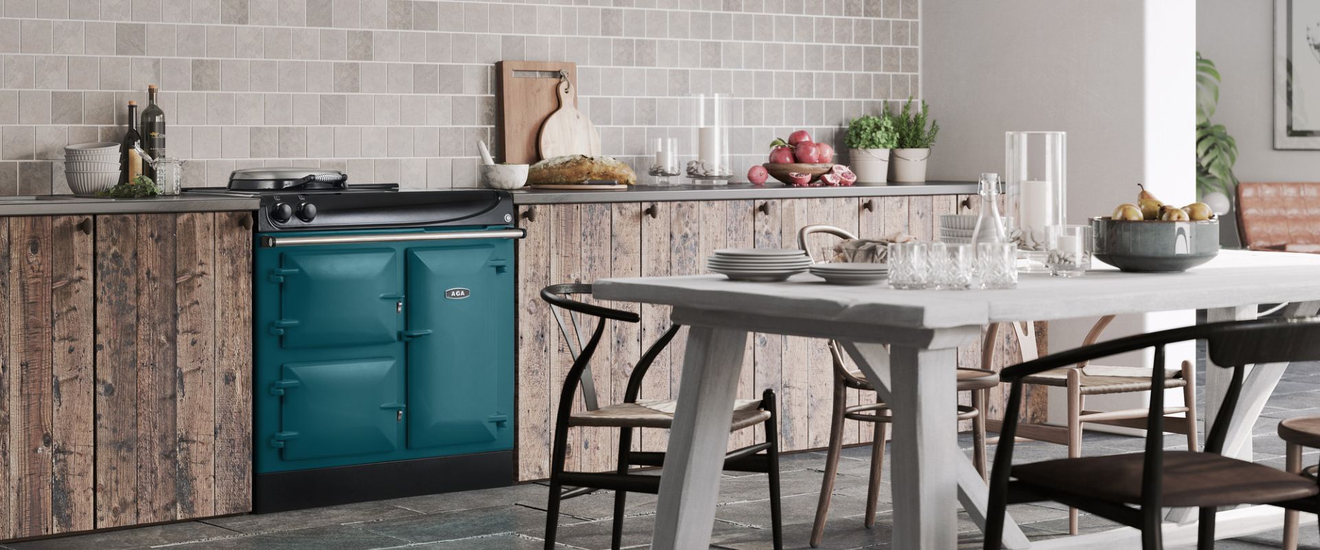 Petrolfarbener AGA Standherd (Range Cooker) in rustikaler Küche mit Holzfronten, Fliesenrückwand und Esstisch; hochwertiger Gusseisen-Ofen mit Kochplatten und Backöfen für gleichmäßiges Garen