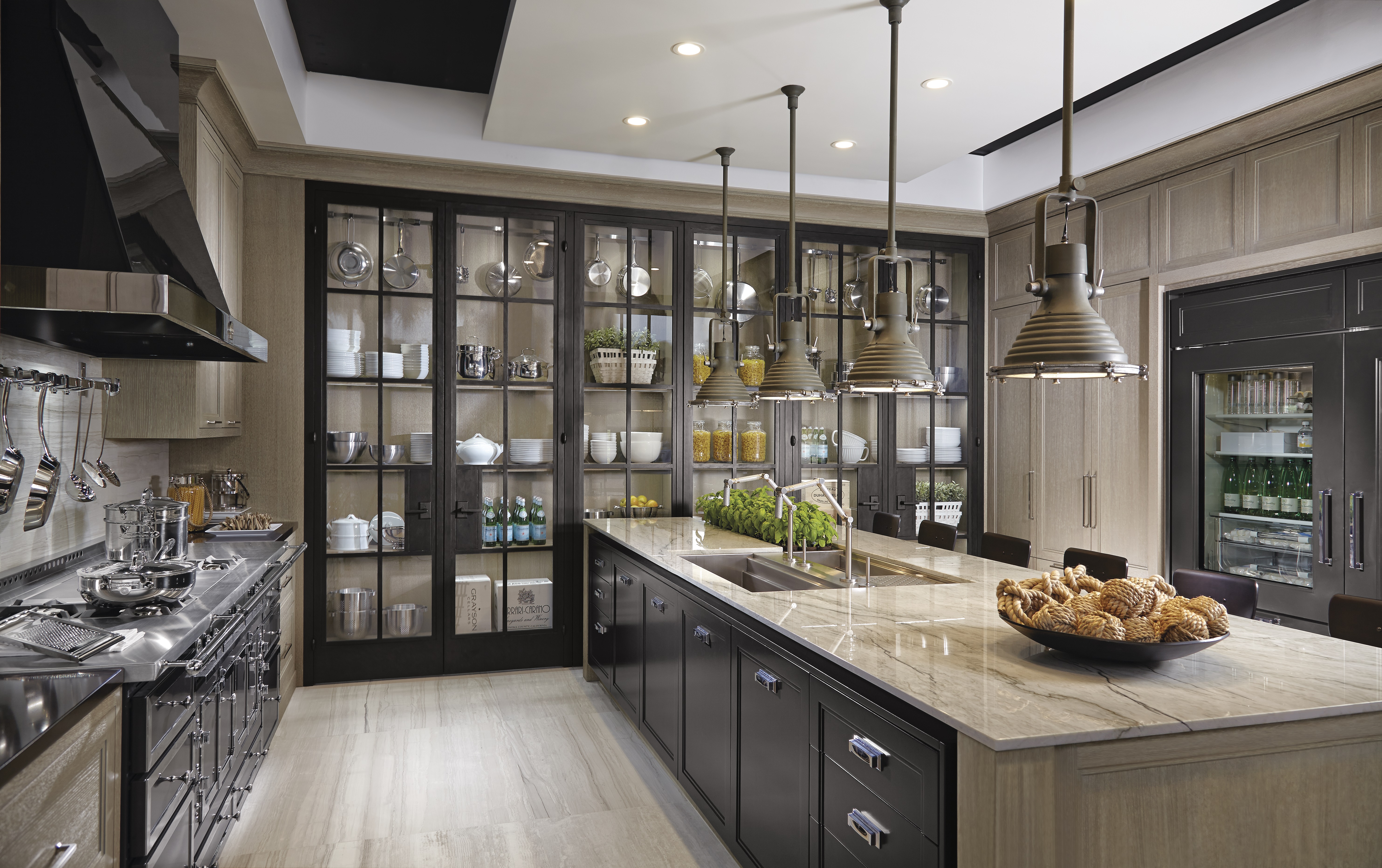 Moderne Designerküche mit Kücheninsel, Glasvitrinen und hochwertiger Ausstattung Großzügige, moderne Küche mit Marmorkücheninsel, hängenden Industrielampen, Glasvitrinen mit Geschirr und Geräten sowie dekorativen Elementen