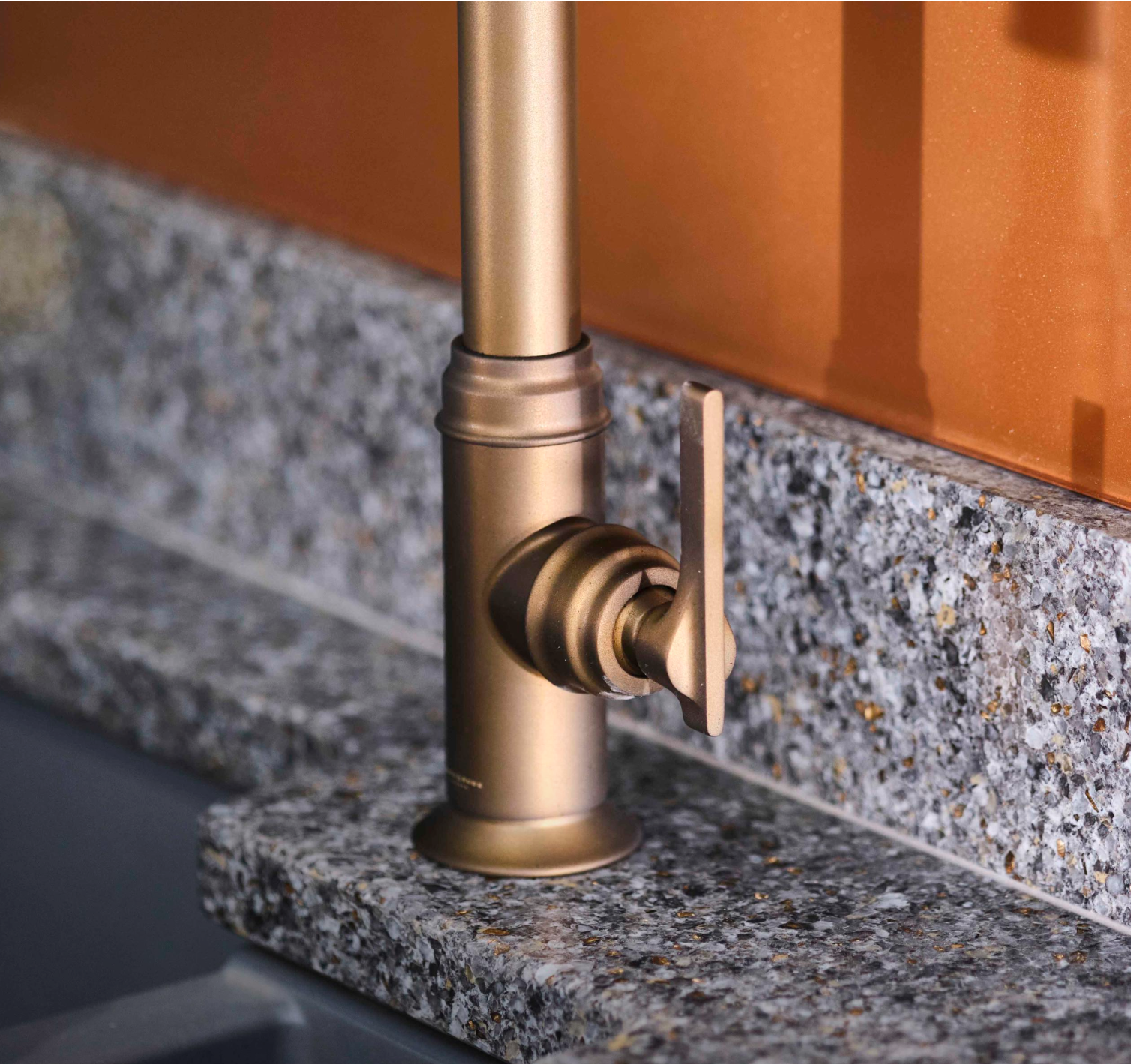 Nahaufnahme der Perrin & Rowe Southbank Monoblock-Küchenarmatur mit integrierter Pull-Down-Ausziehbrause: kannelierter Sockel und seitlicher Hebel auf Granit-Arbeitsplatte im Mid-Century-Stil