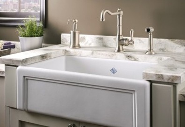 Moderner Landhausstil Spülstein aus Keramik mit Armaturen und Marmormuster-Arbeitsplatte in eleganter Küche Weiße Keramikspüle im Landhausstil mit silberner Armatur, Seifenspender und Marmorarbeitsplatte in einer modernen Küche