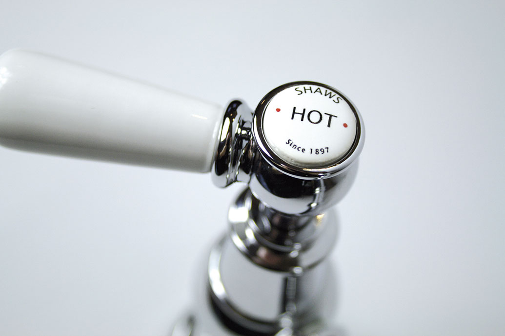 Nahaufnahme eines Shaws Armaturgriffs mit weißem Keramikaufsatz und der Aufschrift HOT für heißes Wasser