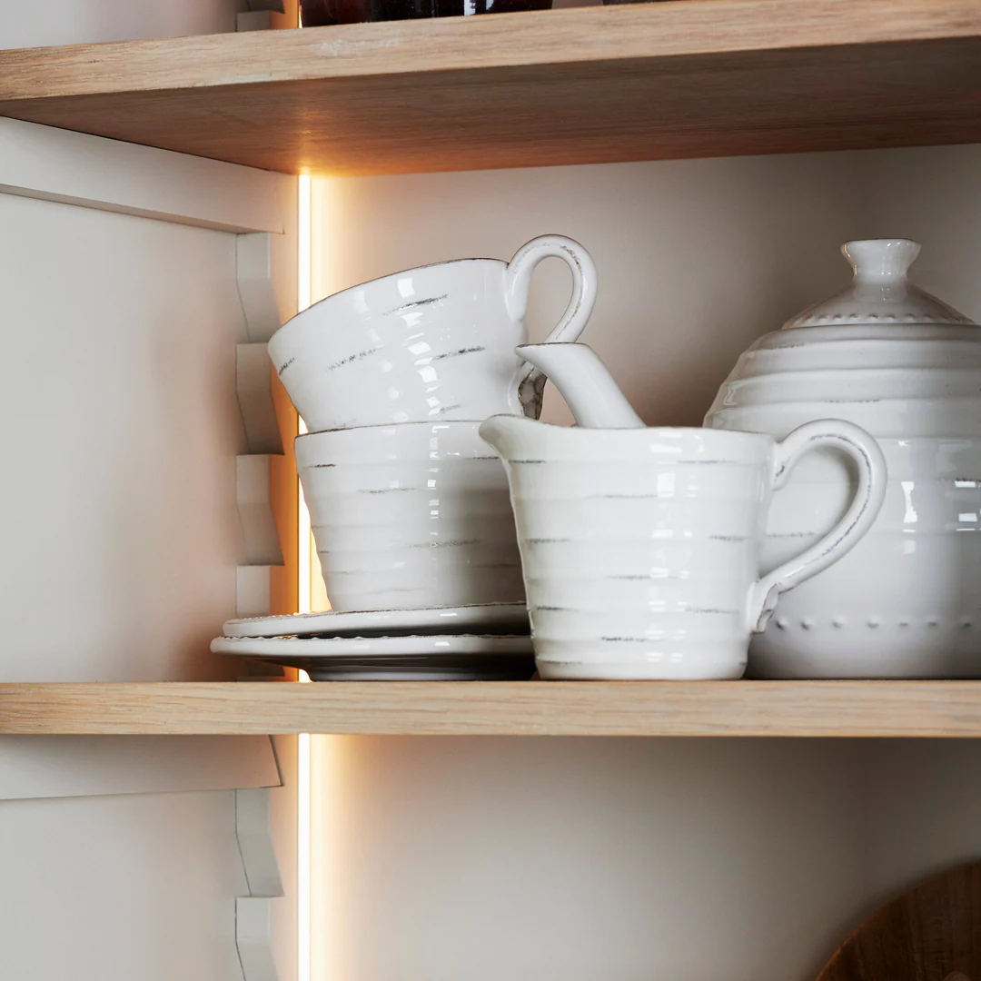 Warmweiße LED-Lichtleiste im Küchenschrank beleuchtet Holzregal mit weißem Keramikgeschirr – energiesparende Akzent- und Arbeitsflächenbeleuchtung für Regale und Vitrinen