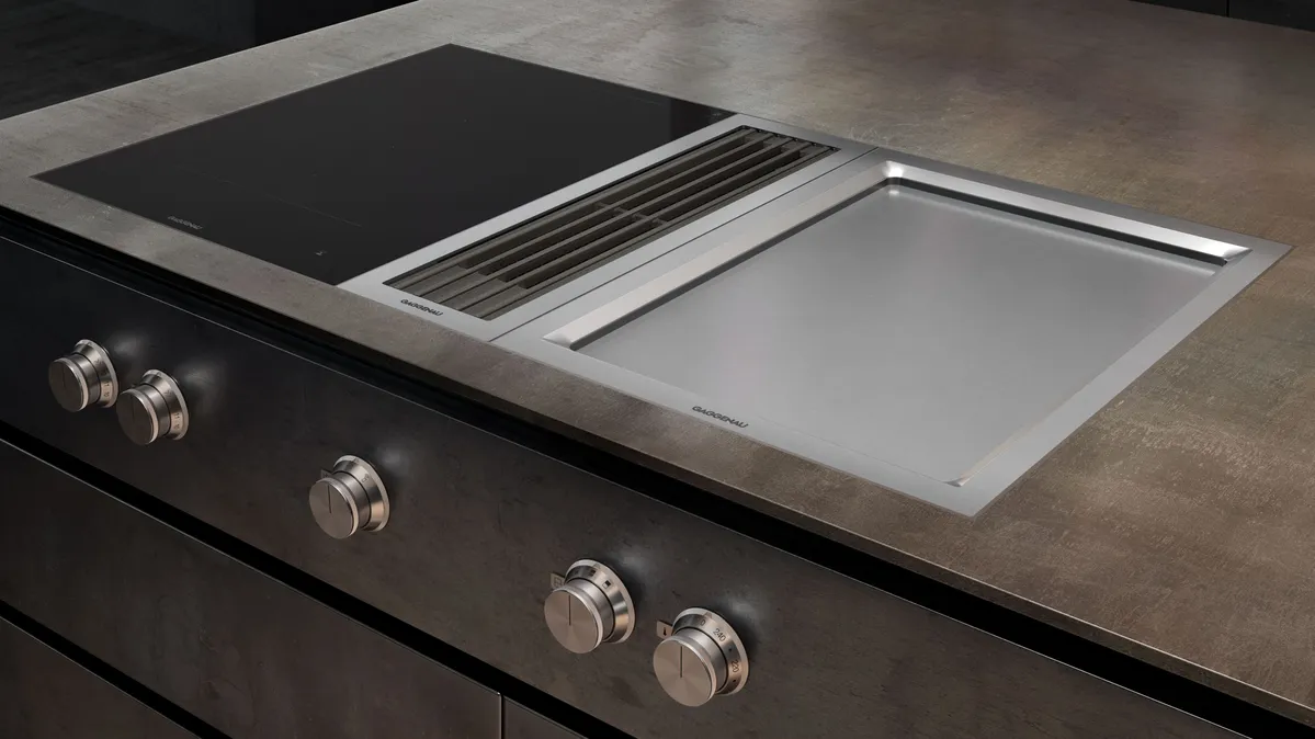 Modernes Kochfeld mit integriertem Lüftungssystem und Edelstahl-Grillplatte Nahaufnahme eines modernen Kochfelds mit eingelassener Grillplatte aus Edelstahl und integriertem Dunstabzug in einer Küchenarbeitsplatte