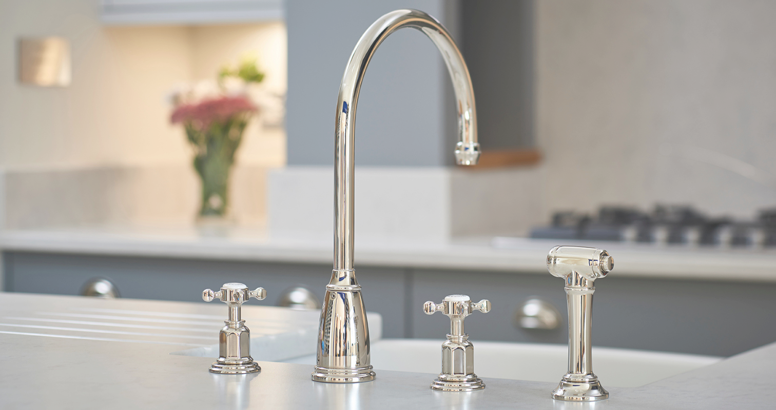 Elegante Küchenarmatur aus Edelstahl mit zwei Griffen und Brause Moderne, glänzende Küchenarmatur aus Edelstahl mit zwei Griffen und separater Spülbrause auf einer Küchenarbeitsplatte