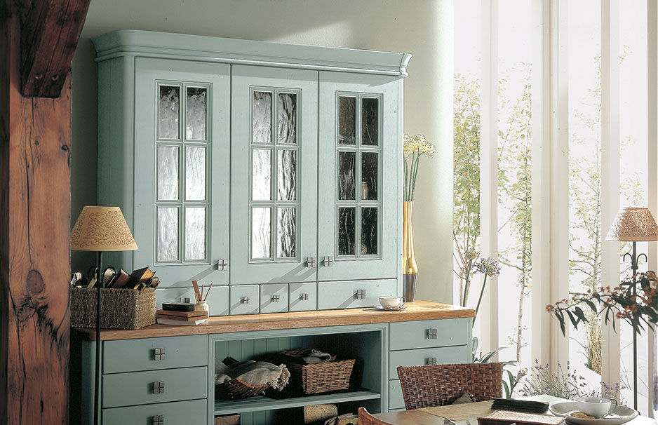 Landhausstil Küchenschrank mit Glastüren in Pastellgrün und Holzelementen Heller Landhausstil Küchenschrank mit Glastüren, Holzarbeitsplatte und Dekoration in einem freundlichen Raum mit Tageslicht