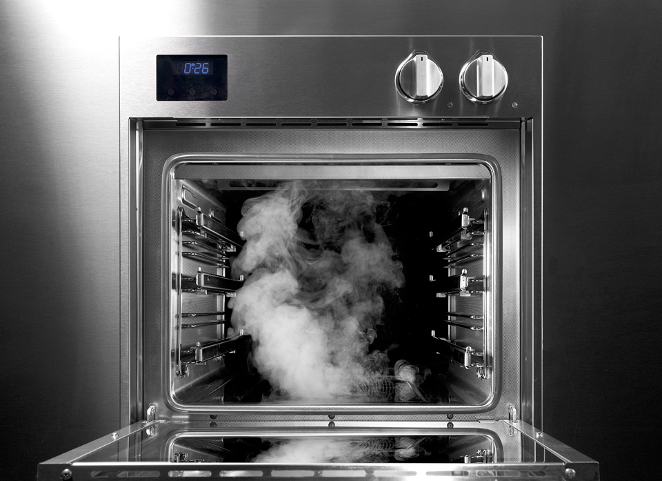 Dampfbackofen aus Edelstahl mit geöffneter Tür und sichtbarem Dampf im Garraum Moderner Edelstahl-Dampfbackofen mit geöffneter Tür, aus dem Dampf austritt, Ansicht von vorne