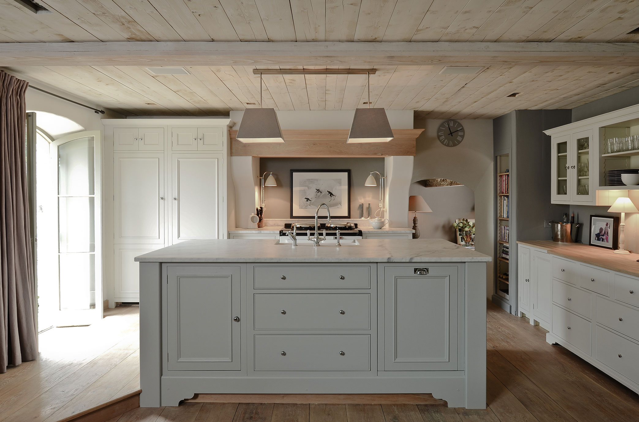 Moderne Landhausküche mit Kücheninsel und hellen Holzelementen Helle Landhausküche mit großer Kücheninsel, Marmorarbeitsplatte, weißen Schränken und Holzdecke