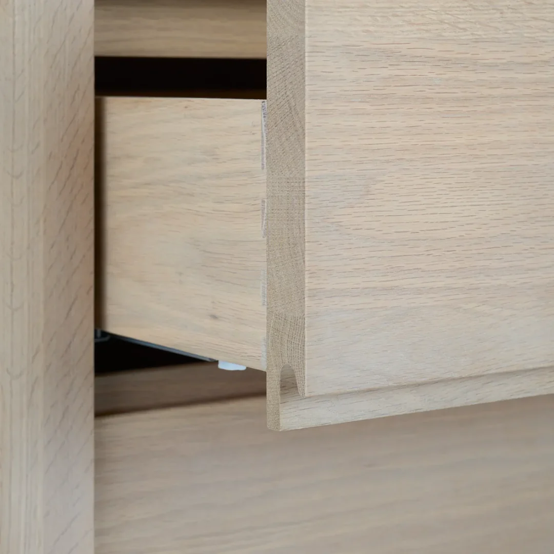 Nahaufnahme einer Massivholz-Schublade aus Eiche mit gefräster Griffnut und stabilem Auszug; zeigt die hochwertige Verarbeitung der Kommode bzw. des Sideboards