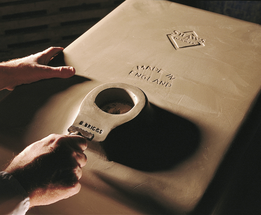 Handwerkliche Prägung eines Keramikprodukts mit 'MADE IN ENGLAND' bei Shaws of Darwen Hand prägt mit Werkzeug die Aufschrift 'MADE IN ENGLAND' auf eine noch ungebrannte Keramikspüle von Shaws of Darwen