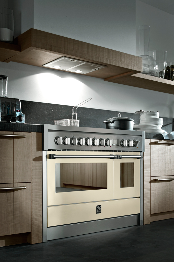 Hochwertiger Standherd mit Edelstahl-Front und cremefarbenen Backofentüren in moderner Einbauküche Großer Standherd mit mehreren Drehknöpfen, cremefarbenen Backofentüren und Edelstahl-Elementen, eingebaut in eine moderne Holzküche mit Ablagebrettern