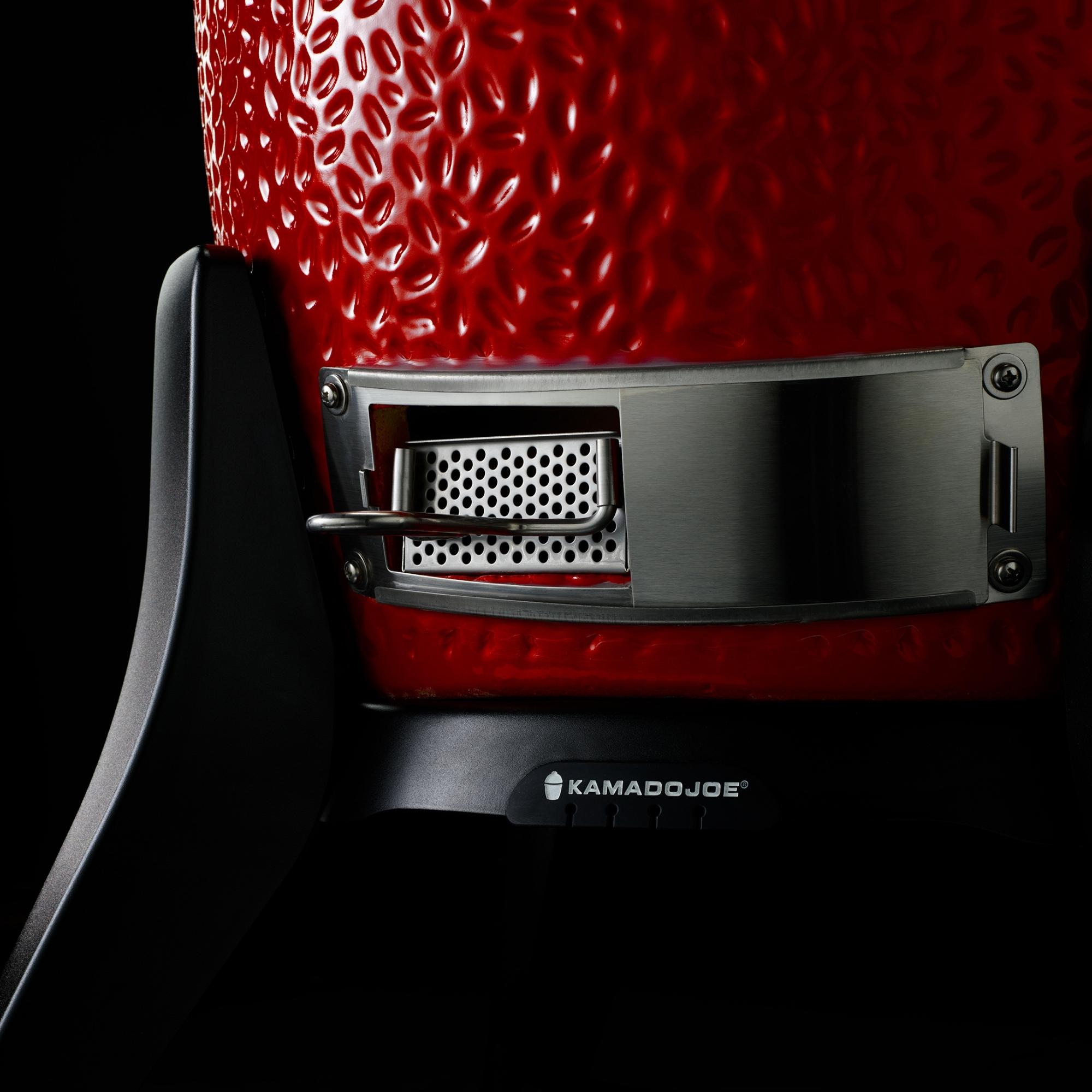 Detailansicht einer Kamado Joe Grill-Luftzufuhr mit Edelstahl-Elementen Nahaufnahme der unteren Luftzufuhr eines roten Kamado Joe Keramikgrills mit Edelstahl-Element und Logo