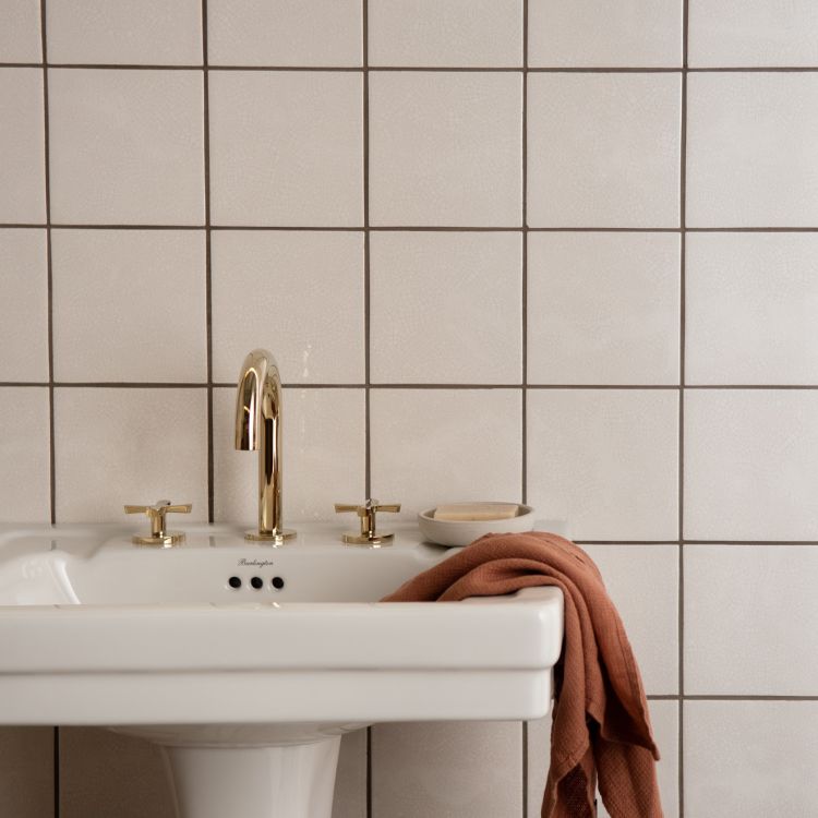 Waschbecken mit goldener Armatur und rostbraunem Tuch