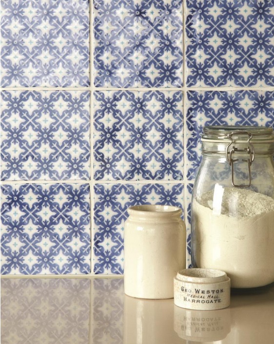 Dekorative blaue und weiße Wandfliesen mit Vorratsgläsern in einer Küche Nahaufnahme von blauen und weißen gemusterten Wandfliesen mit einem Glasbehälter mit Mehl, einem Keramiktopf und einem kleinen Porzellangefäß auf einer Arbeitsfläche